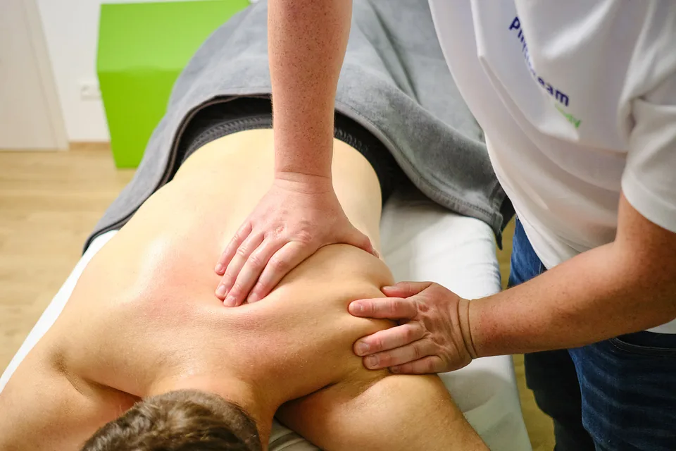 Physiotherapeut behandelt die Schulter einer Patientin